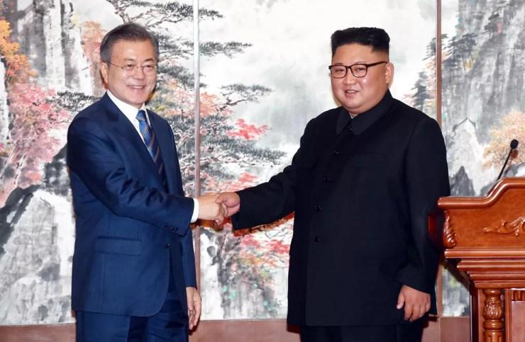 O presidente sul-coreano Moon Jae-in (esq.) e o líder norte-coreano Kim Jong-un apertam as mãos durante encontro em Pyongyang, na Coreia do Norte. Novos acordos da reaproximação incluem o fechamento do sítio norte-coreano de testes de mísseis de Tongchang-ri, a redução da possibilidade de confrontos entre seus exércitos ao redor da fronteira que compartilham, e uma candidatura conjunta aos Jogos Olímpicos de 2032 — Foto: Pyongyang Press Corps Pool via AP