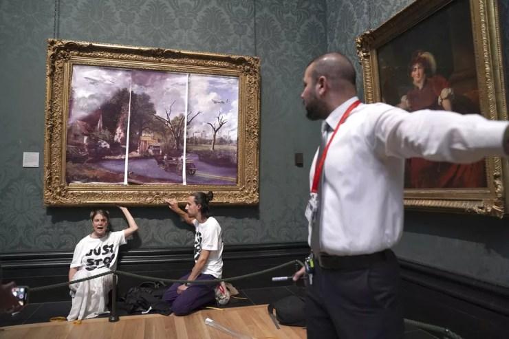 Ativistas do clima cobrem quadro da National Gallery, em Londres, com 'uma visão apocalíptica do futuro' e colam as mãos em obra durante protesto — Foto: Kirsty O'Connor/PA via AP