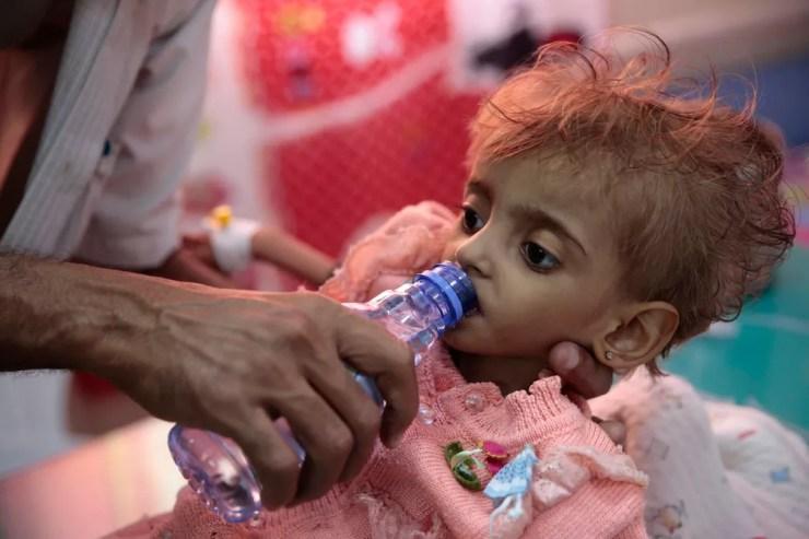 Pai dá água para filha desnutrida em um centro de alimentação em um hospital em Hodeida, no Iêmen, em 27 de setembro  — Foto: Hani Mohammed/AP