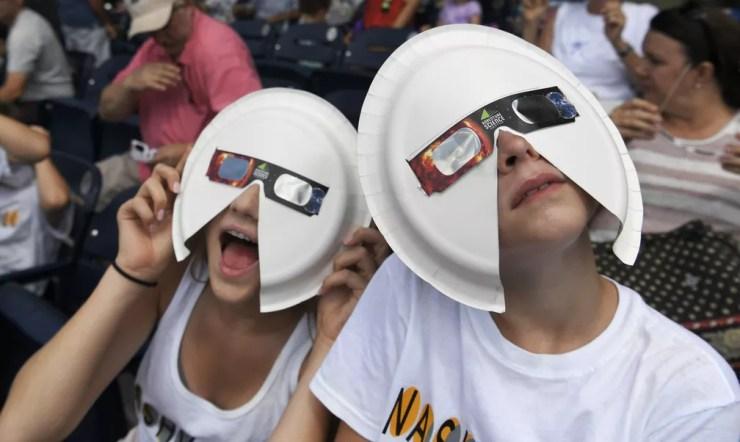 Annie Penuel e Lauren Peck usam máscaras feitas de pratos de papel em Nashville Tennessee. (Foto: Shelley Mays/AP)