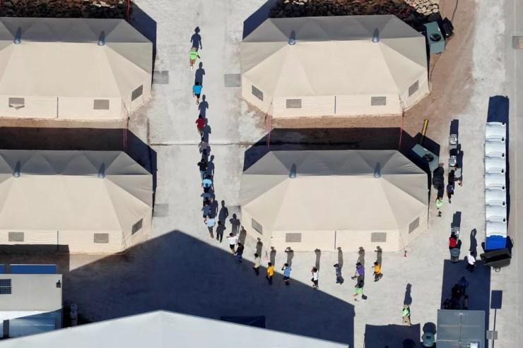 Crianças imigrantes, mmuitas delas separadas dos pais sob a política de tolerância zero do governo Trump, caminham em fila entre barracas de composto perto da fronteira mexicana em Tornillo, no Texas, EUA (Foto: Mike Blake/Reuters)