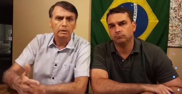 O candidato do PSL à Presidência, Jair Bolsonaro, ao lado do filho Flávio Bolsonaro, durante transmissão no Facebook — Foto: Reprodução