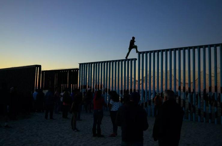  Um homem hondurenho caminha pelo topo do muro na fronteira que separa o México e os Estados Unidos, em Tijuana, no México — Foto: Gregory Bull/AP