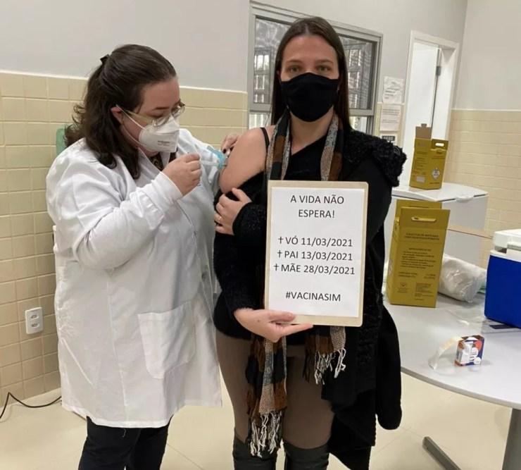 Tallyta Cerqueira mostra cartaz enquanto é vacinada  — Foto: Arquivo pessoal/Tallyta Cerqueira