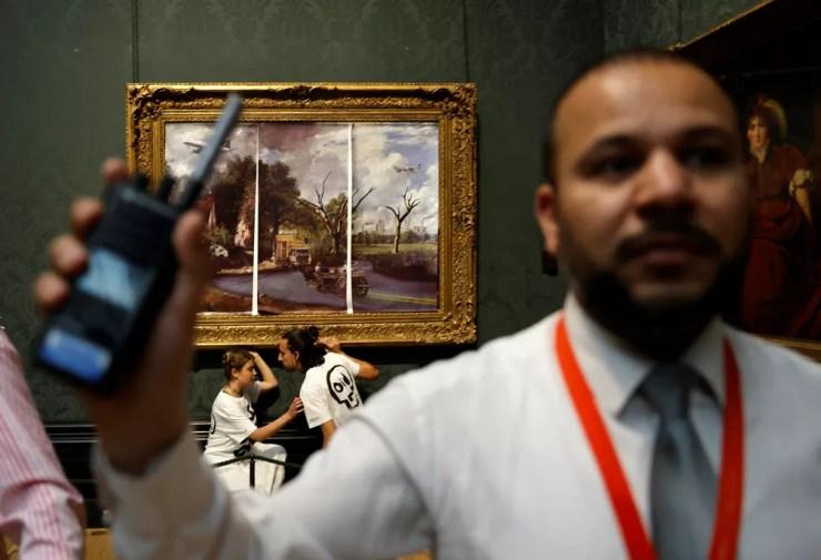 Ativistas do clima cobrem quadro da National Gallery, em Londres, com 'uma visão apocalíptica do futuro' e colam as mãos em obra durante protesto — Foto: Carlos Jasso/AFP