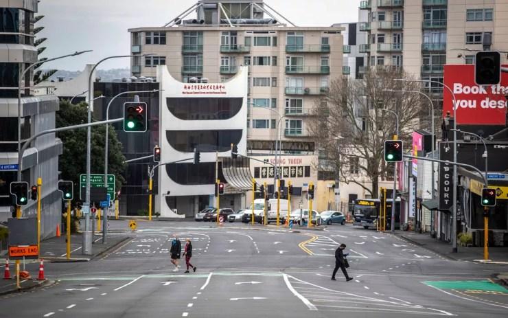 Pessoas cruzam ruas quase vazias do distrito comercial de Auckland, na Nova Zelândia, durante lockdown em agosto — Foto: Michael Craig/NZ Herald via AP