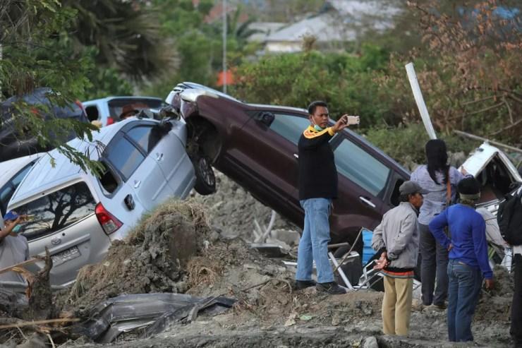 Homem tira selfie diante de carros que colidiram após o tremor e o tsunami em Petobo, em Palu, na Indonésia  — Foto: Jorge Silva/ Reuters