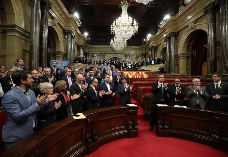 O presidente catalão Carles Puigdemont e deputados aplaudem aprovação de declaração da independência no Parlamento catalão em meio a assentos vazios dos deputados dos partidos PSC, Ciudadanos e PP  (Foto: Reuters/Albert Gea)