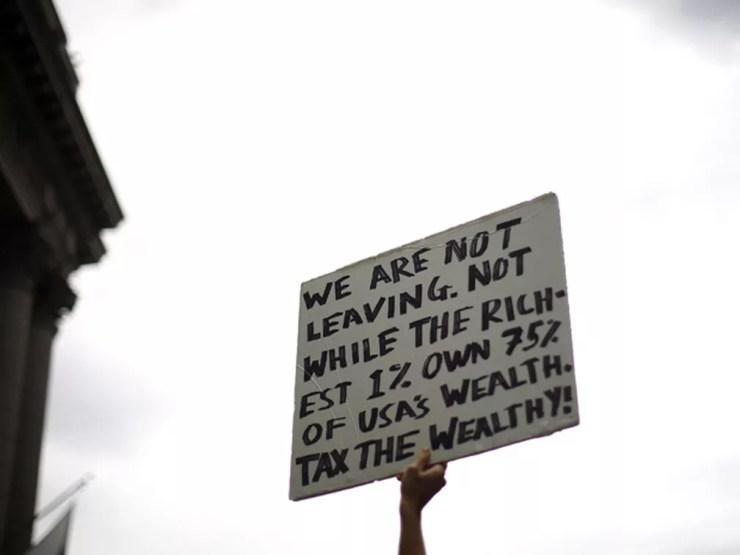 'Não vamos sair. Não enquanto os 1% mais ricos tiverem 75% da riqueza dos EUA. Taxem os ricos!', diz cartaz em protesto contra 'ganância corporativa' em Wall Street — Foto: Reuters / Eric Thayer