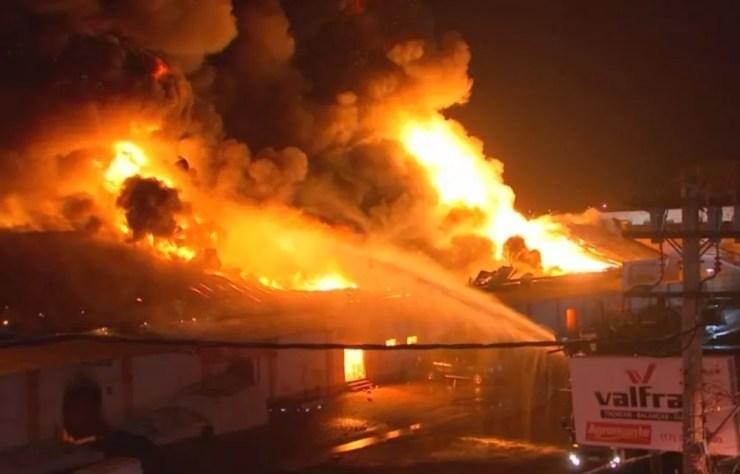 Bombeiros jogam água para tentar controlar as chamas no telhado da loja (Foto: Reprodução/TV TEM)