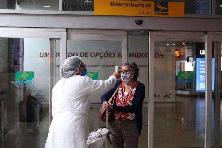 Funcionária mede temperatura de passageiro no aeroporto de Congonhas, em São Paulo  — Foto: REUTERS/Amanda Perobelli
