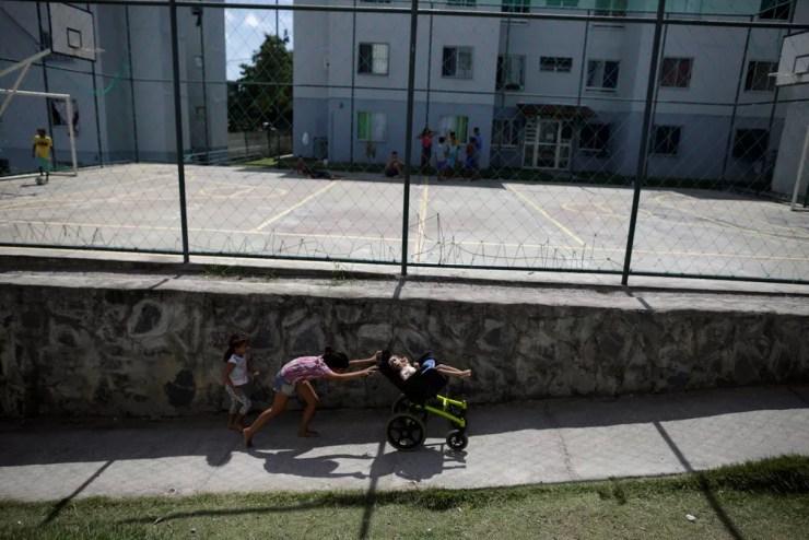 Luana Vieira, que tem dois anos e nasceu com microcefalia, é empurrada na cadeira de rodas pela irmã Vitoria Evillen, próximo a quadra do condomínio em que moram, em Olinda — Foto: Ueslei Marcelino/Reuters