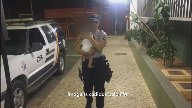 Cabo da PM levando bebê a delegacia (Foto: Reprodução)
