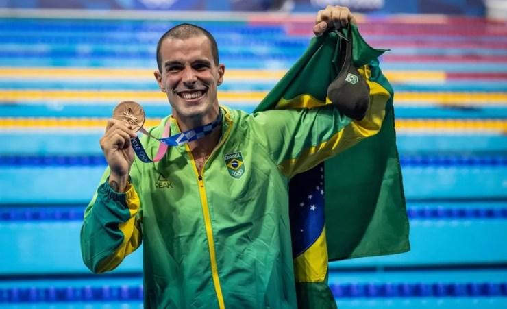 Bruno Fratus com a medalha de bronze dos 50m livre da natação nas Olimpíadas de Tóquio e a bandeira do Brasil — Foto: Jonne Roriz/COB