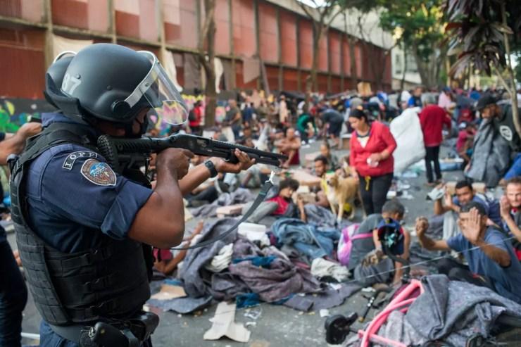 Policial aponta arma para usuários de droga durante operação da Polícia Civil na Cracolândia, nesta sexta-feira (27) em São Paulo. — Foto: TIAGO QUEIROZ/ESTADÃO CONTEÚDO