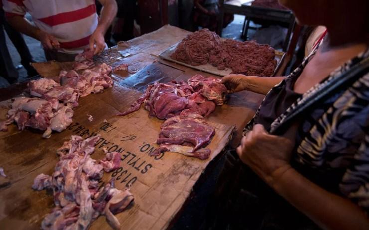 Consumidores examinam carne estragada, misturada à carne fresca, oferecida em Mercado em Maracaibo, na Venezuela, no dia 19 de agosto — Foto: AP Photo/Fernando Llano