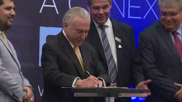 O presidente Michel Temer assina decreto que regulamenta medida provisória no Salão Internacional do Automóvel em São Paulo — Foto: Reprodução/TV Globo 
