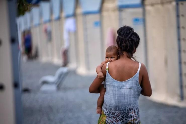 Mulher caminha com um bebê no colo entre as cabanas de um abrigo da Operação Acolhida em Boa Vista — Foto: Fábio Tito/g1