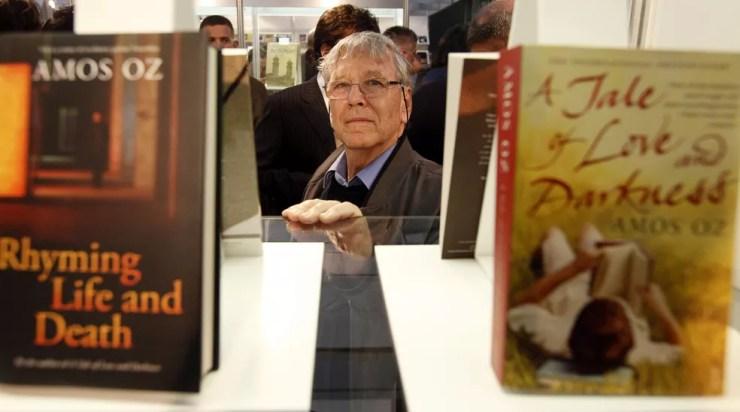 O escritor israelense Amos Oz, o principal convidado da feira anual de livros de Budapeste, posa entre seus livros no salão do Centro Cultural Millenaris. Foto de abril de 2010 — Foto: Gergely Botar/AFP/Arquivo