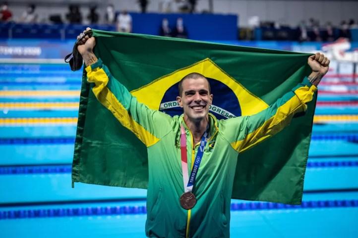 Bruno Fratus com a medalha de bronze dos 50m livre da natação nas Olimpíadas de Tóquio e a bandeira do Brasil — Foto: Jonne Roriz / COB