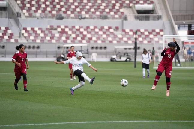 Jogadora do Afeganistão (de branco) no amistoso contra uma equipe feminina do Catar — Foto: Divulgação