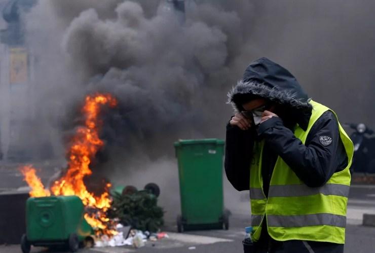 Manifestante protege o rosto da fumaça durante confrontos com a polícia em Paris, no sábado (8). — Foto: Stephane Mahe/Reuters