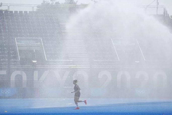 Jogadora alemã de hóquei sobre a grama corre em meio a jato d'água no estádio — Foto: Michael Kappeler/picture alliance via Getty Images