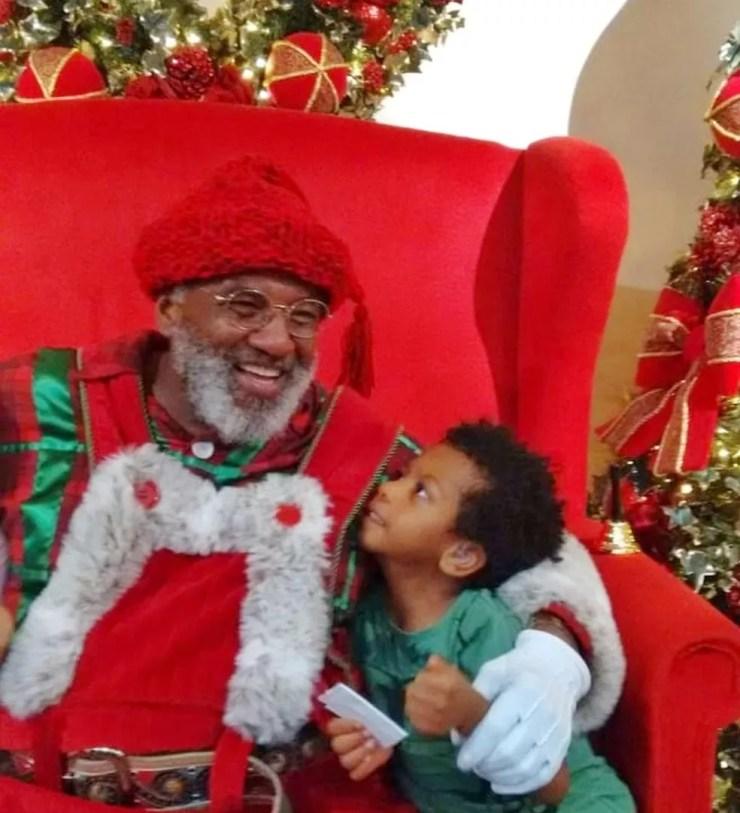 Rubens ao lado do garoto Daniel, que ficou eufórico ao encontrar o Papai Noel negro — Foto: Arquivo pessoal/ Adriana Simões