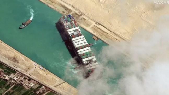 O cargueiro de 400 metros Ever Given ficou preso diagonalmente no Canal de Suez em 23 de março por quase uma semana, causando o bloqueio de uma das principais rotas marítimas comerciais do mundo — Foto: Getty Images/BBC