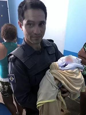 Tenente Marcelo Conde segura o bebê após ajudar a salvá-lo (Foto: Divulgação/PM)