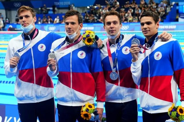 Com máscaras no queixo, russos exibem medalha de prata na natação — Foto: REUTERS