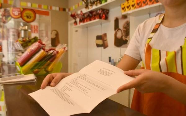 Funcionária recebe currículo para trabalho temporário em loja de chocolates em Campinas (Foto: Clara Rios/G1)